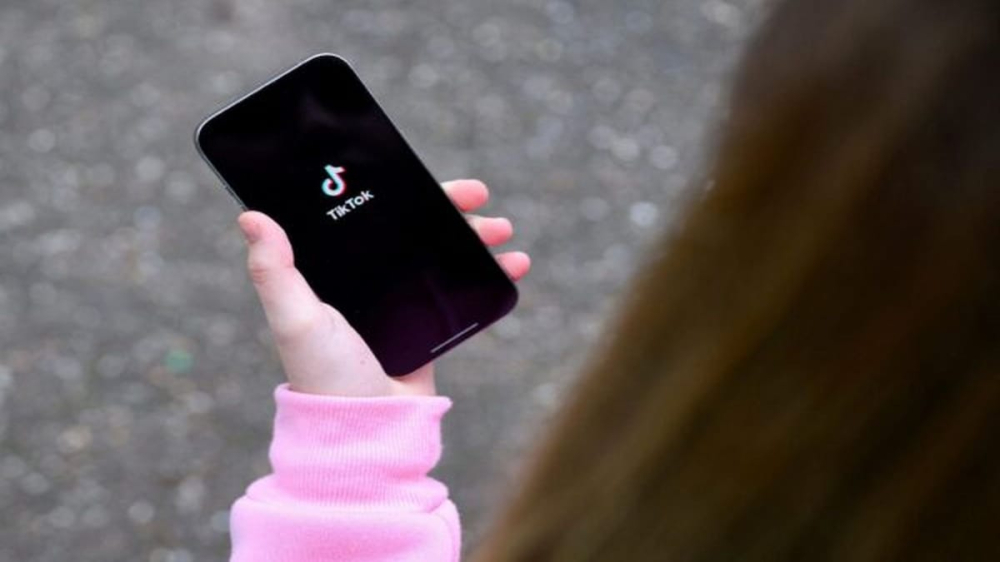 tiktok_ny_lawsuit.jpg 青少年手持显示TikTok标志的手机